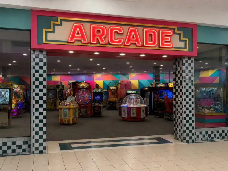Arcade storefront in a mall with a neon sign, checkered columns, and colorful game machines inside